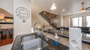 A modern kitchen with a granite countertop, stainless steel sink, and a clock on the wall. - Midtown Houston City View Home (Houston)