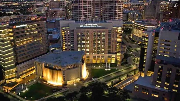 A high-rise hotel with multiple floors, a central courtyard, and a prominent building with a lit facade. - Midtown Houston City View Home (Houston)