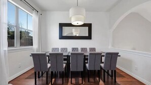 A dining room with a large table and six chairs, a hanging light fixture, and a framed mirror on the wall. - Midtown Houston City View Home (Houston)