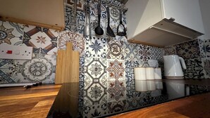 Une cuisine avec des carreaux décoratifs, une planche à découper en bois, un range-couteaux et une machine à café.
