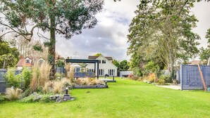 A residential property with a well-maintained lawn, a patio area, and a house with a modern design.