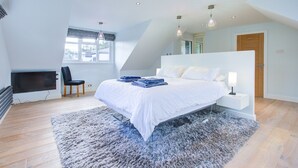 A modern bedroom with a large bed, a desk, and a chair.