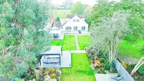 A residential property with a well-maintained lawn, a patio area, and a house with a sloped roof.