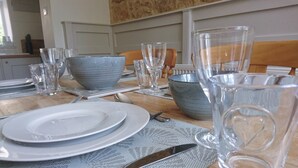Une table à manger dressée avec des assiettes, des couverts et des verres à boire transparents.