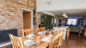 A dining area with a wooden table set for six, surrounded by wooden chairs. - Meadowfields (Whitby)
