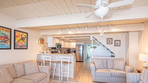 A spacious living area with a kitchen, a dining area, and a staircase leading to an upper level. - Beautiful Direct Ocean Front Townhome in Sea Village with Relaxing Ocean Views! (Ocean City)