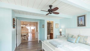 A bedroom with a bed, a ceiling fan, a nightstand, a lamp, and a framed picture on the wall. - Beautiful Direct Ocean Front Townhome in Sea Village with Relaxing Ocean Views! (Ocean City)