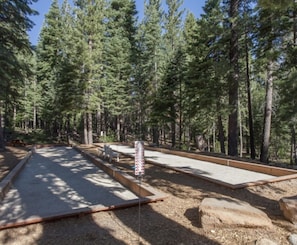 A campground with picnic tables and a fire pit area surrounded by tall pine trees. - Luxury Northstar Ski Cabin • Free Shuttle to Lifts • Fireplace • Xbox • Hot Tub (Truckee)
