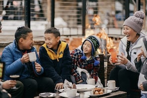 A group of people sitting around a table with food and drinks, outdoors. - Luxury Northstar Ski Cabin • Free Shuttle to Lifts • Fireplace • Xbox • Hot Tub (Truckee)