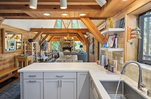 A modern kitchen with a central island, built-in cabinets, and a stone fireplace.