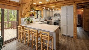 A modern kitchen with wooden beams, a central island with bar stools, and a view of the outdoors. - Sleeps 8 • 3BR • Lux Northstar • Free Shuttle • Fireplace • Xbox • Gym • Hot Tub (Truckee)