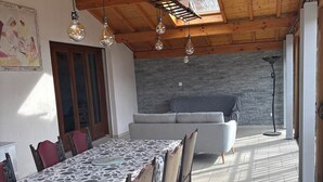 A dining area with a long table, chairs, and hanging light fixtures.