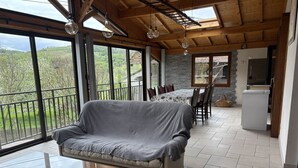 A cozy room with a covered sofa, a dining table with chairs, and a kitchen area.