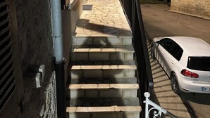 A staircase leading to a wooden porch with a car parked outside.