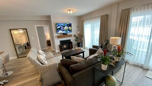 Un salon moderne avec une cheminée, un canapé et un téléviseur.