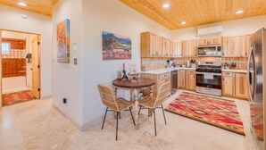 Una cocina moderna con armarios de madera, una isla central y una zona de comedor con sillas de mimbre.