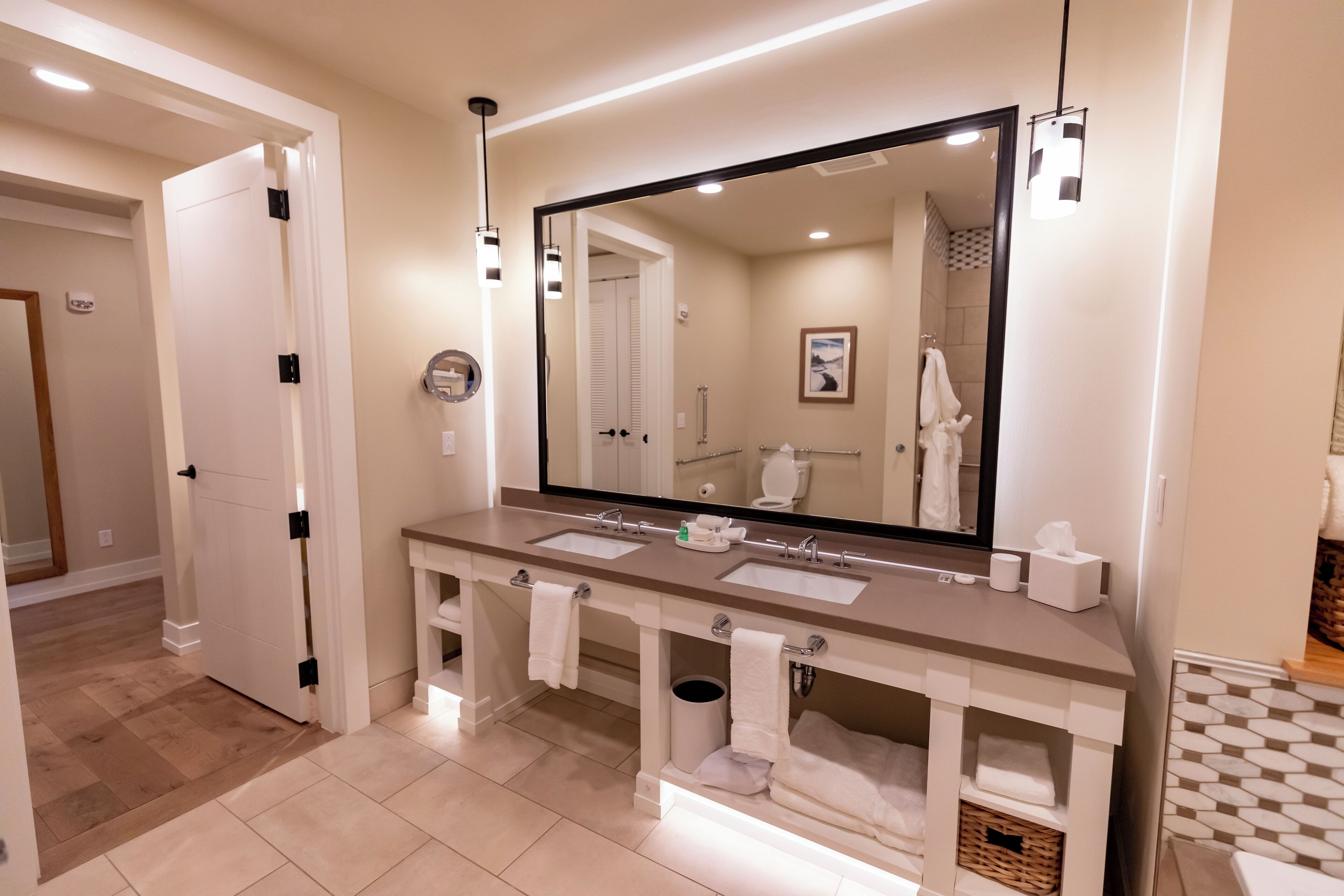 A modern bathroom with a large mirror, two sinks, and a towel rack.