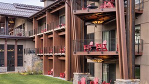 A multi-story building with outdoor seating areas, stone walls, and a metal roof. - The Inn at SentryWorld (Stevens Point)