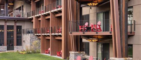 A multi-story building with outdoor seating areas, stone walls, and a metal roof.