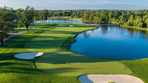 A golf course with bunkers, a water hazard, and a forested area. - The Inn at SentryWorld (Stevens Point)