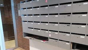 A row of grey mailboxes with labels, a glass door, and a brick wall. - Amazing 2-bedroom Apartment With Amazing Sea-view (Ostend)