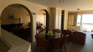 A spacious living area with a dining table and chairs, a kitchen area with granite countertops, and a view of the outdoors through large windows. - Amazing 2-bedroom Apartment With Amazing Sea-view (Ostend)