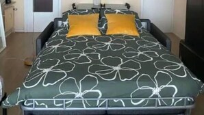 A bedroom with a bed, two doors, a lamp, and a vase with flowers. - Stunning 1-bed Apartment in Oostende Beach-view (Ostend)