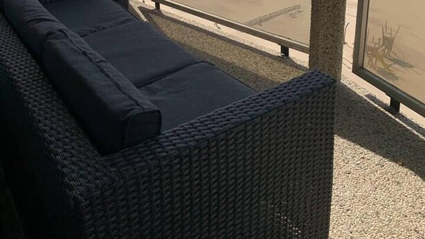A balcony with a wicker sofa and a view of the beach. - Stunning 1-bed Apartment in Oostende Beach-view (Ostend)