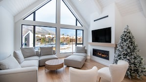 Una sala de estar moderna con ventanas grandes, una chimenea y un árbol de Navidad.