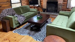 Ein gemütliches Wohnzimmer mit zwei grünen Sofas, einem Holztisch und einem Kamin.