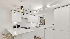 Una cocina moderna con armarios blancos, una isla central e iluminación colgante.