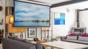 En moderne stue med et stort fladskærms-tv, grå sofaer, et hvidt sofabord og en pejs.