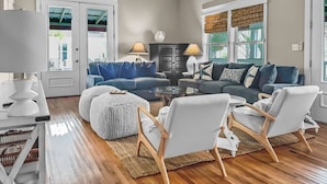 A living room with a sofa set, ottomans, and chairs, a coffee table, and a lamp.
