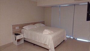 A bedroom with a bed, a bedside table with a phone, and a TV mounted on the wall. - Saint Paul Plaza Flat Particular (Brasília)