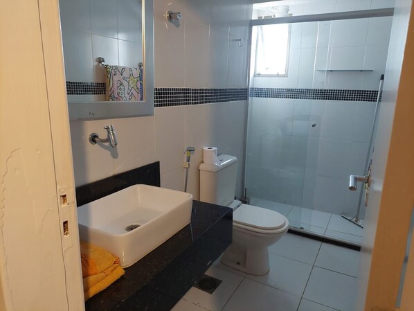 Un baño con lavamanos, inodoro y ducha blancos.