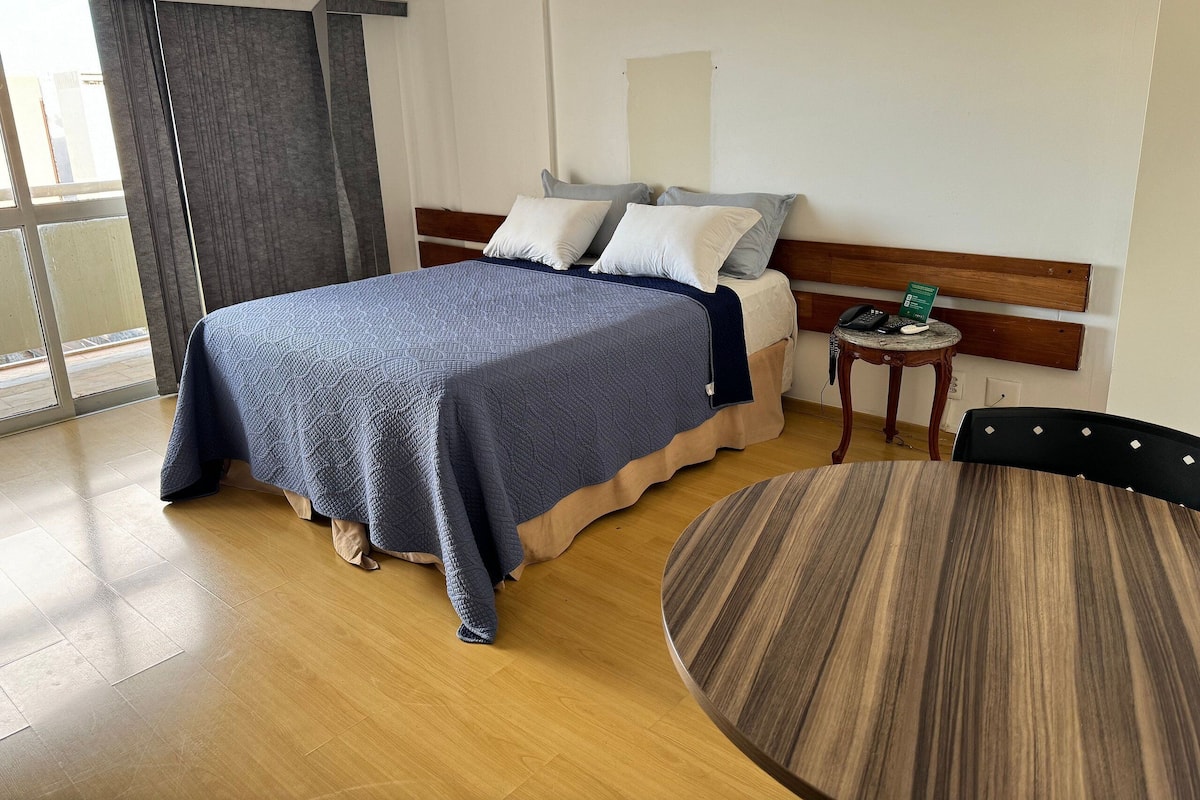 A hotel room with a bed, bedside table, and a round dining table.