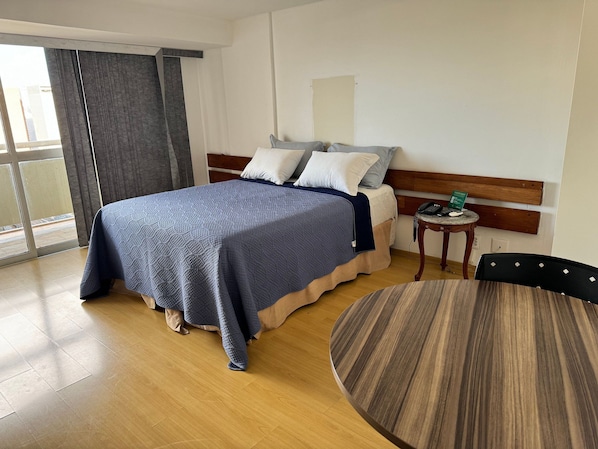 A hotel room with a bed, bedside table, and a round dining table. - Saint Paul Plaza Flat Particular (Brasília)
