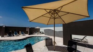 A rooftop pool area with lounge chairs and umbrellas. - Saint Paul Plaza Flat Particular (Brasília)