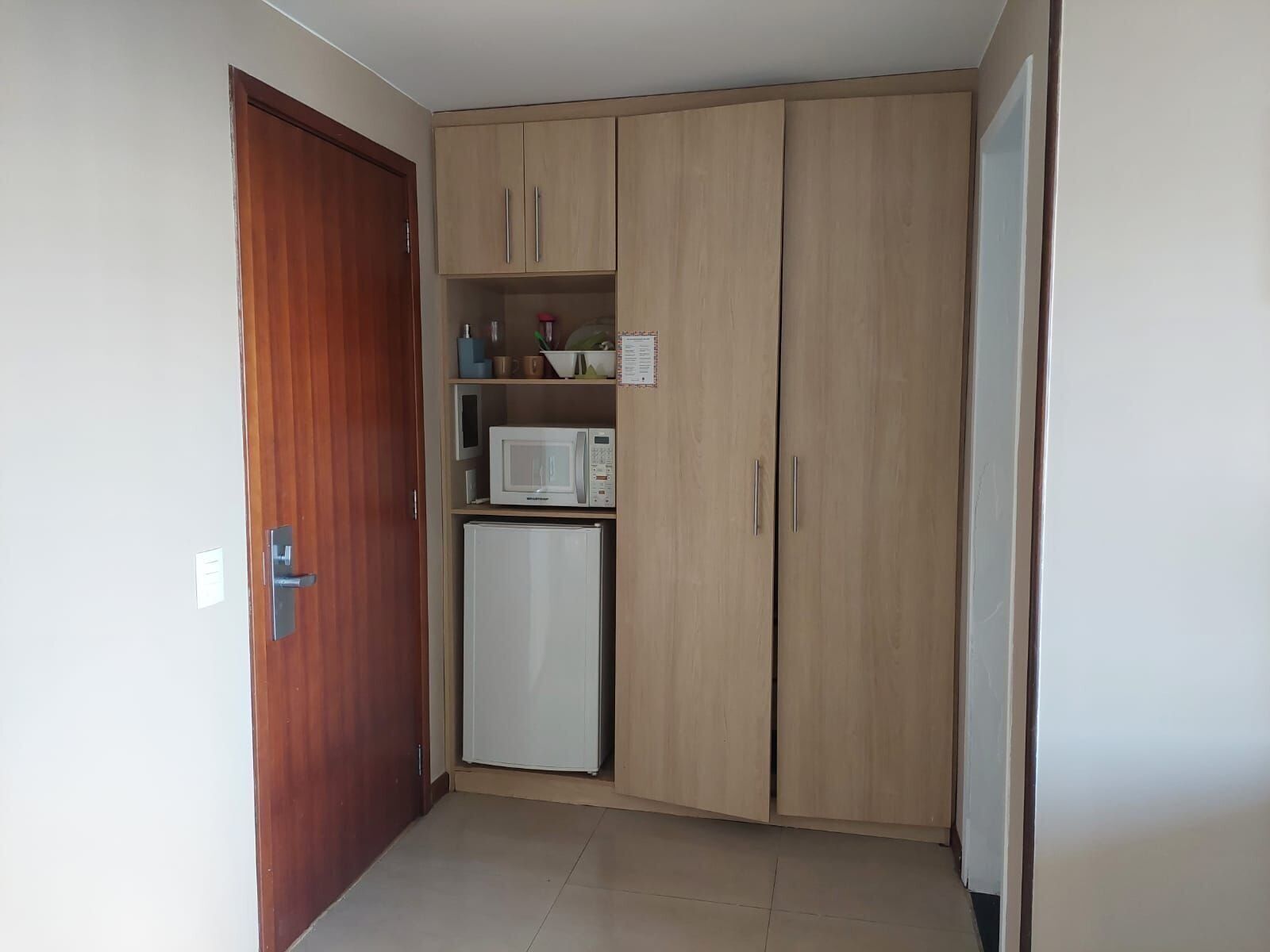 A small kitchen with wooden cabinets, a microwave, and a refrigerator.