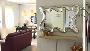 Ein modernes Wohnzimmer mit einem roten Sofa, einem Holztisch und einem großen Spiegel an der Wand.
