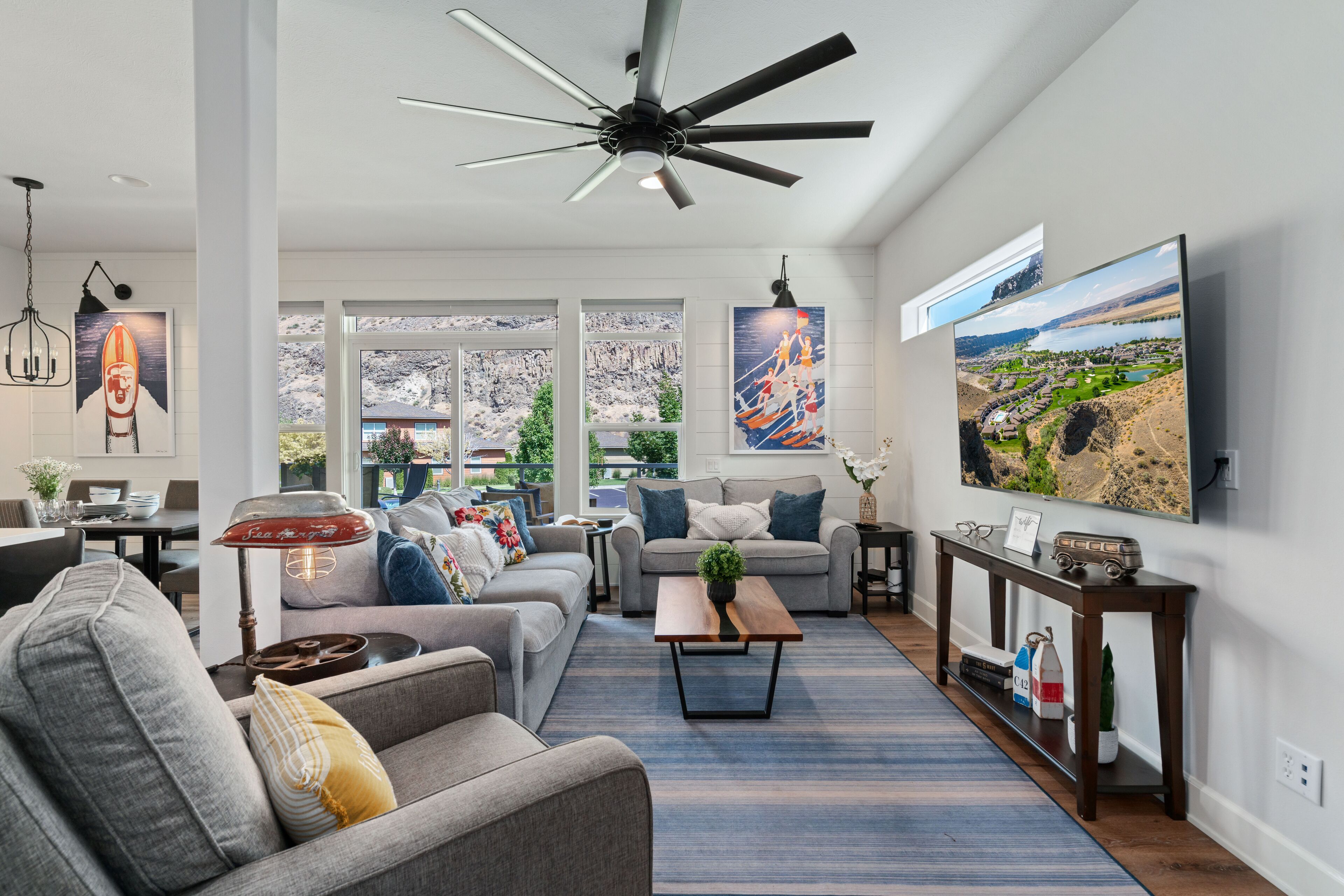 A spacious living room with a large TV, comfortable seating, and a ceiling fan.