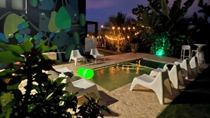 A pool area with lounge chairs and a small pool, surrounded by greenery and decorative lights. - Minutes from the beach, modern home with ocean views. Pet friendly!   (Rincón)