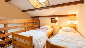 Un dormitorio con dos literas de madera, un tragaluz y una lámpara de noche.