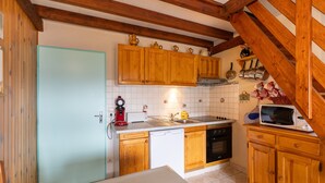Una cocina con armarios de madera, microondas, fregadero y cafetera.