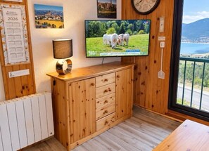 A wooden cabinet with drawers, a television on the wall, and a calendar on the left.