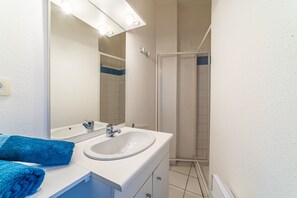 A bathroom with a white sink, mirror, and blue towels.
