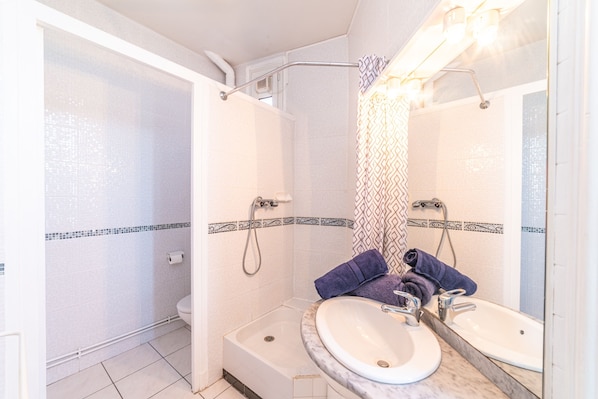Une salle de bain avec une douche, deux lavabos et un miroir.
