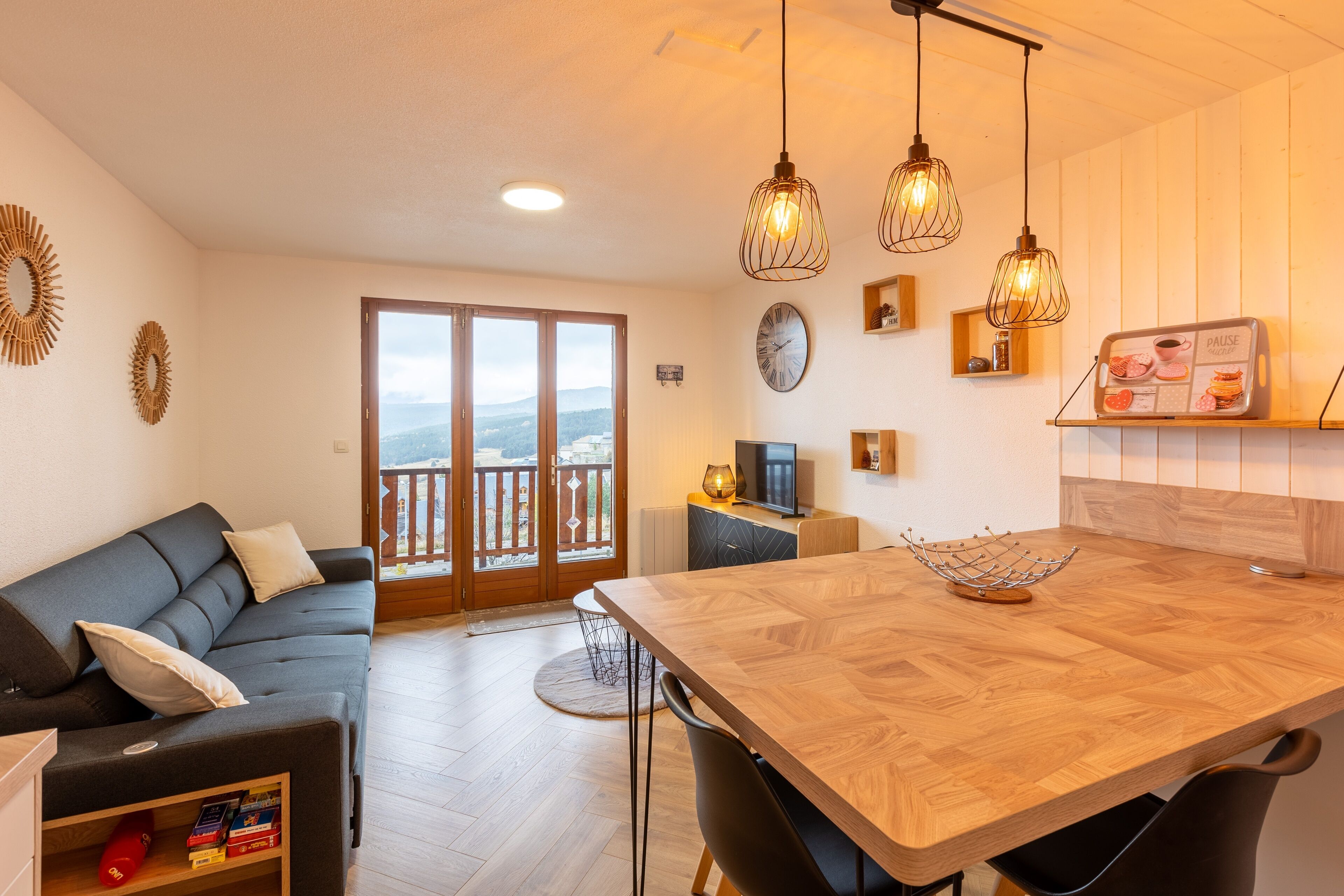 A modern living room with a sofa, dining table, and kitchen area.