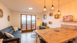 A modern living room with a sofa, dining table, and kitchen area.