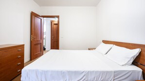 A bedroom with a wooden bed, a wooden dresser, and a door leading to another room. - Berni - One Bedroom Apartment, Sleeps 2 (Florence)